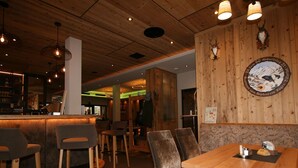 A restaurant interior with wooden tables and chairs, a bar area, and a wall-mounted sign. - Cosy apartment for 6 guests with WIFI, TV and terrace (Hart Im Zillertal)