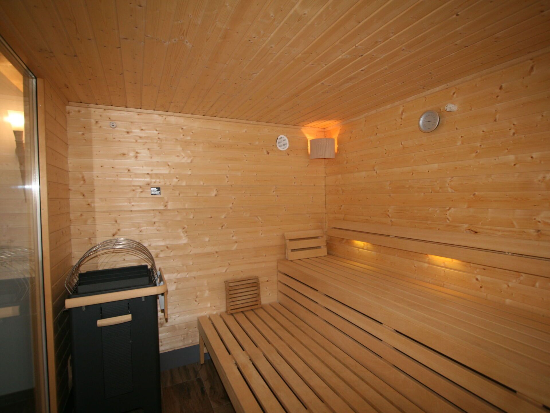 Un sauna en bois, doté de bancs et d’une porte en verre.