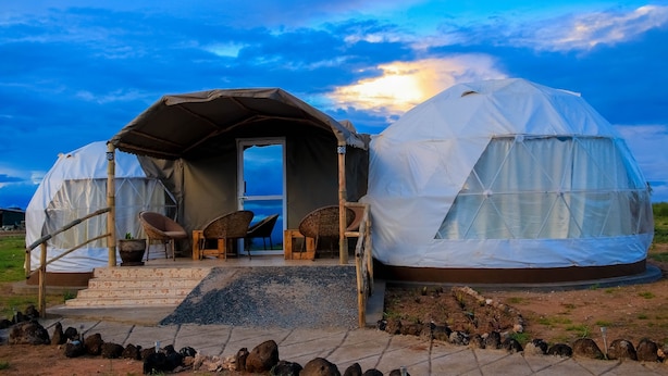 Two yurts with a covered entrance and seating area, set in a grassy field with a clear sky. - Amanya Sleeps 4 with Tent Views (Risa Amboseli)