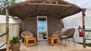 A tent with a door, two chairs, a small table, and a potted plant. - Amanya Sleeps 4 with Tent Views (Risa Amboseli)