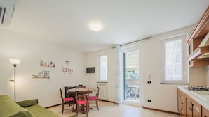 Un espace de vie compact comprenant un coin repas, une kitchenette et un canapé vert.