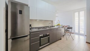 A modern kitchen with stainless steel appliances, white cabinetry, and a large window providing natural light. - Nice apartment for 4 guests with A/C, WIFI, TV and balcony (Sestri Levante)