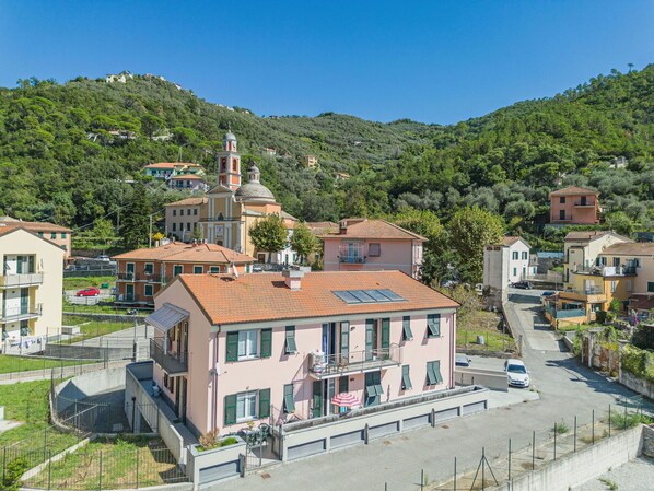 A residential area with a prominent church, a pink building with balconies, and a hillside in the background.