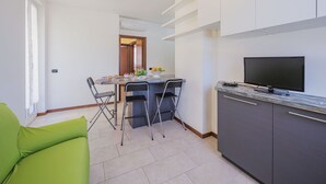 A compact kitchen with a dining area, a green sofa, and a flat-screen TV. - Nice apartment for 4 guests with A/C, WIFI, TV and balcony (Sestri Levante)