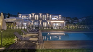 Une maison moderne à deux étages, dotée d’une piscine, d’un espace extérieur aménagé et d’un patio bien éclairé.