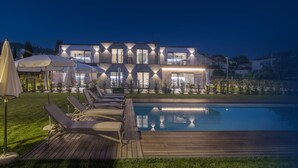 Ein modernes, zweistöckiges Haus mit Swimmingpool, Außenbereich mit Sitzgelegenheiten und einer gut beleuchteten Terrasse.