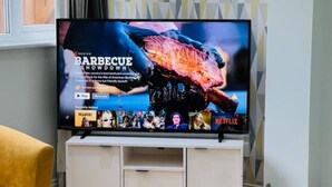 A television on a white entertainment unit with a Netflix logo and a series titled "BARBECUE SHOWDOWN" displayed on the screen. - 4 Bed House - Sleeps 9 - Garden - Parking - Wifi (Birmingham)