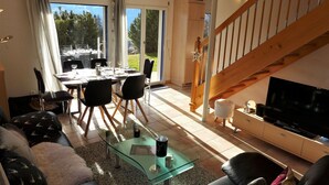 A modern living room with a glass coffee table, a sofa, a TV, and a dining area with a table and chairs. - Wonderful  villa for 6 people with WIFI, TV and terrace (Bluche)