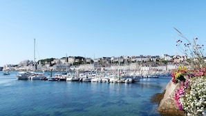 Un puerto deportivo con barcos amarrados, un cielo azul despejado y edificios al fondo.