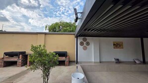 A patio area with a barbecue grill, a small tree, and a water dispenser.
