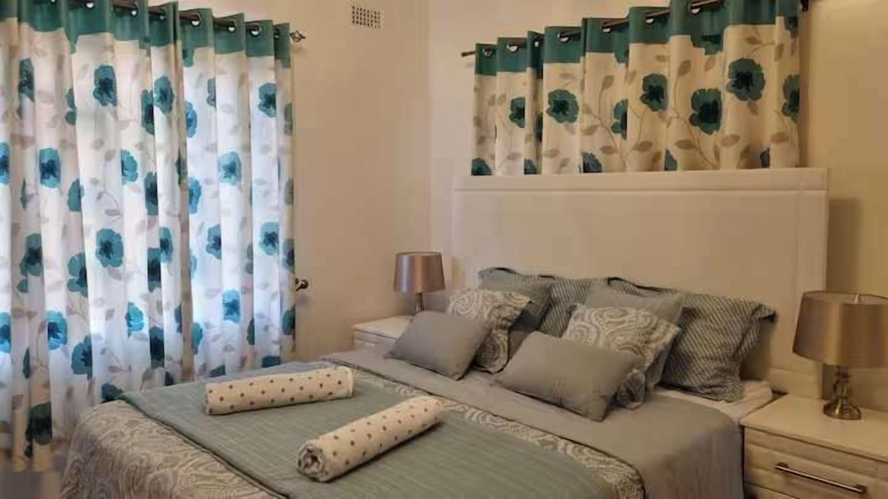 A bedroom with a bed, pillows, a nightstand, and curtains.