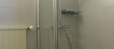 Ducha envuelta en vidrio con cabezal de ducha de mano y panel de control en la pared.