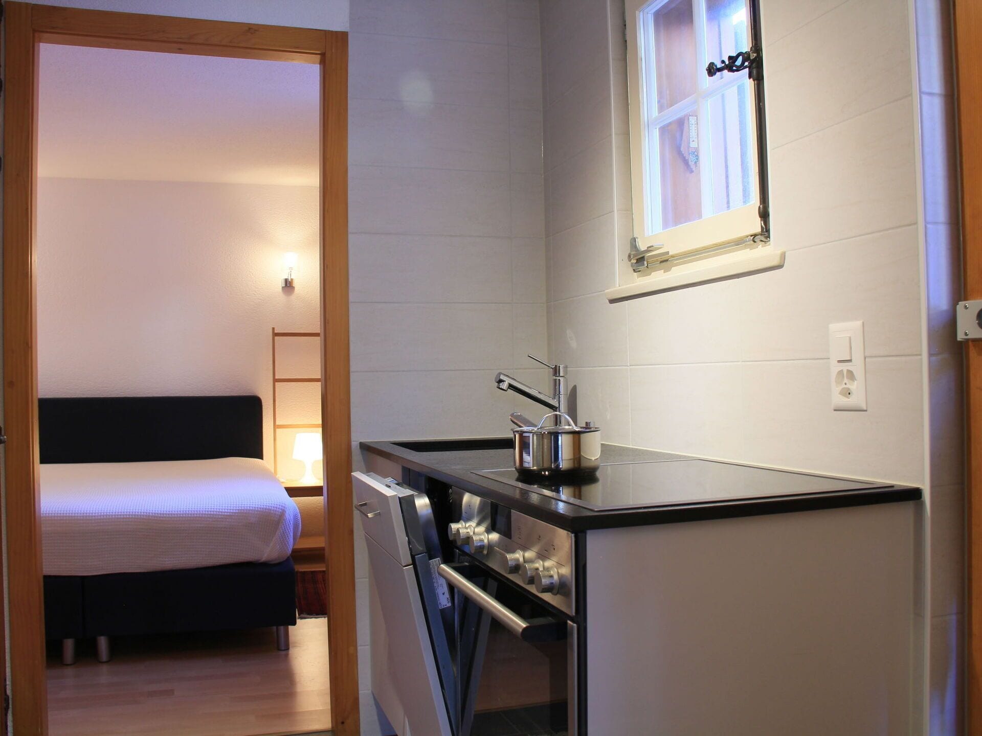 A compact kitchenette with a stove, a small sink, and a window.