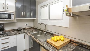 Eine moderne Küche mit einer Granit-Arbeitsplatte, einer Edelstahl-Spüle und einer Mikrowelle.