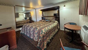 Una habitación de hotel con literas, un escritorio, una silla, un aparador, un espejo y una lámpara en el techo.