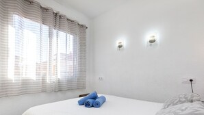 A hotel room with a bed, a window with curtains, and two wall-mounted lights. - Nice apartment for 4 guests with A/C, WIFI, pool, TV and balcony (Lloret De Mar)