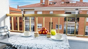 A balcony with a table set for breakfast, including apples, a glass of juice, and a cake. - Nice apartment for 4 guests with A/C, WIFI, pool, TV and balcony (Lloret De Mar)