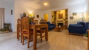 Ein Wohnzimmer mit einem Holzesstisch, blauen Sofas und einem Kamin.