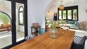 A dining area with a wooden table, wicker chairs, and a vase with flowers. - Beautiful private villa for 6 people with WIFI, private pool, A/C, TV and patio (Miami Platja)