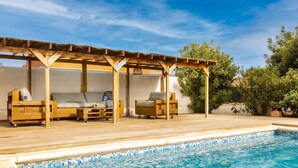 A poolside area with wooden deck seating, a covered patio, and a clear blue pool. - Beautiful private villa for 6 people with WIFI, private pool, A/C, TV and patio (Miami Platja)