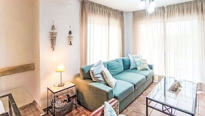 Een woonkamer met een bank, een glazen salontafel, een lamp en een klein bijzettafeltje.