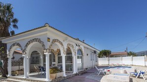 A white building with stone arches and a tiled roof, a pool area with lounge chairs, and a clear blue sky. - Stunning private villa for 6 guests with private pool, A/C, WIFI, TV and terrace (Miami Platja)