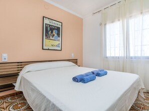 Una habitación de hotel con una cama, un cartel en la pared y una ventana con cortinas.