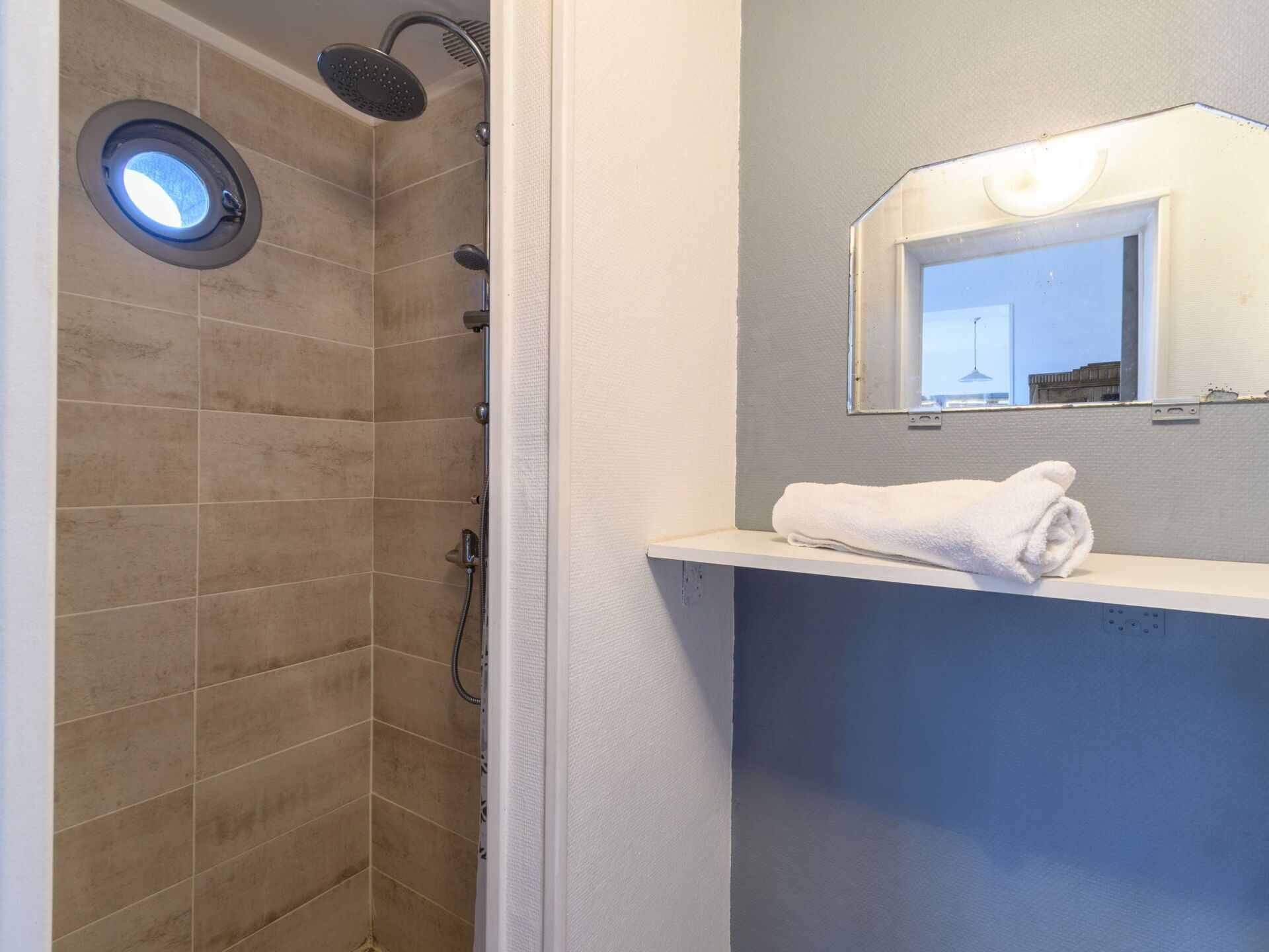 Une salle de bain avec une douche, un lavabo et un miroir.