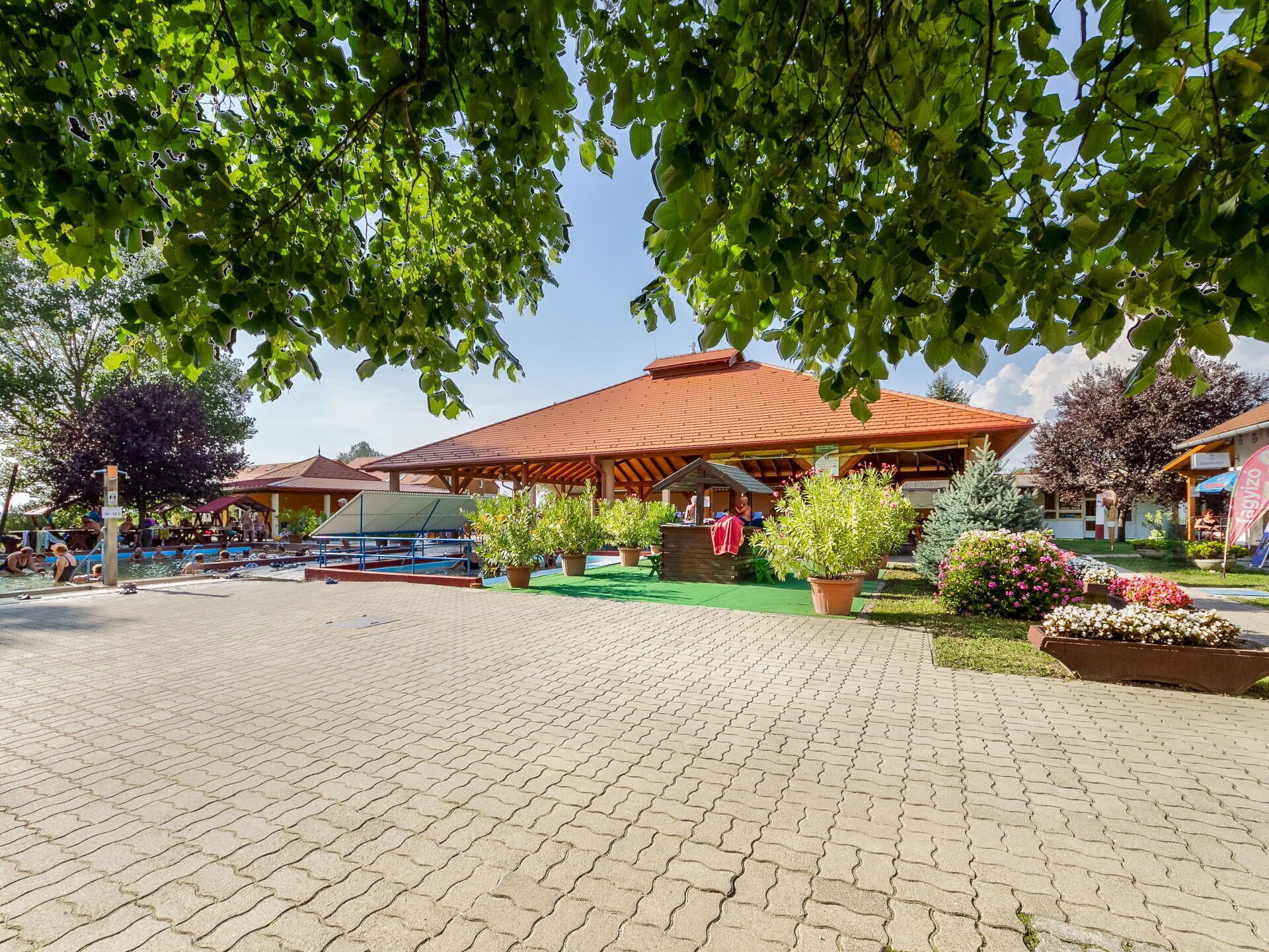 A courtyard with a swimming pool, covered seating areas, and potted plants.