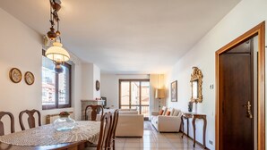 A spacious living area with a dining table, chairs, a sofa, and a wooden door. - Beautiful apartment for 4 people with WIFI, TV, balcony and pets allowed (Nonio)