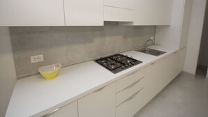 Una cocina moderna con armarios blancos, estufa a gas y lavamanos.