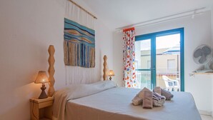 Une chambre à coucher avec un lit, des lampes de chevet, une décoration murale et une vue sur le balcon extérieur.