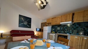 Un coin repas avec une table en verre mise pour le petit-déjeuner, comprenant des croissants et du jus d’orange.