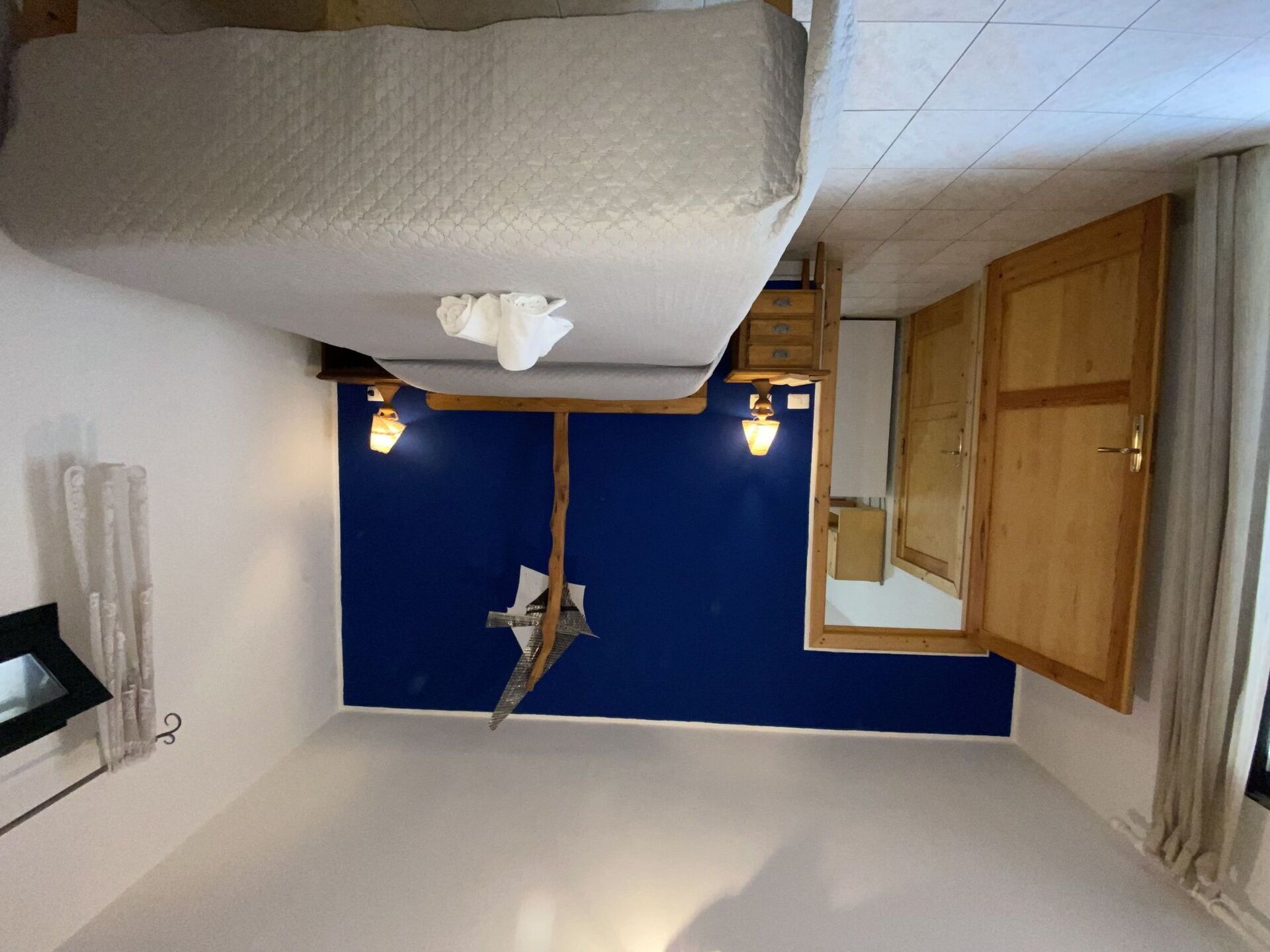 A room with a bunk bed, a blue accent wall, a wooden cabinet, and a mirror.