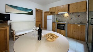 A compact kitchen with wooden cabinets, a built-in oven, and a dining area with a table and chairs.