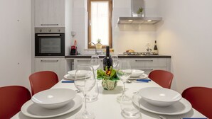 Une cuisine moderne avec des armoires blanches, un four encastré et une fenêtre au-dessus de l’évier.