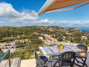 Enjoy al fresco dining on this serene outdoor terrace overlooking a picturesque coastal landscape.