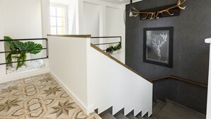 Een modern interieur met een trap, een donkere muur met decoratie van een hertengewei, en een lijstwerk met een afbeelding van een hertengewei.
