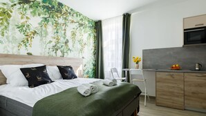 Een moderne hotelkamer met een groot bed, een bureau en een kitchenette.