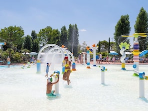 Ein Wasserpark mit verschiedenen Wasserspielgeräten, einem Schwimmbecken und Liegebereichen.