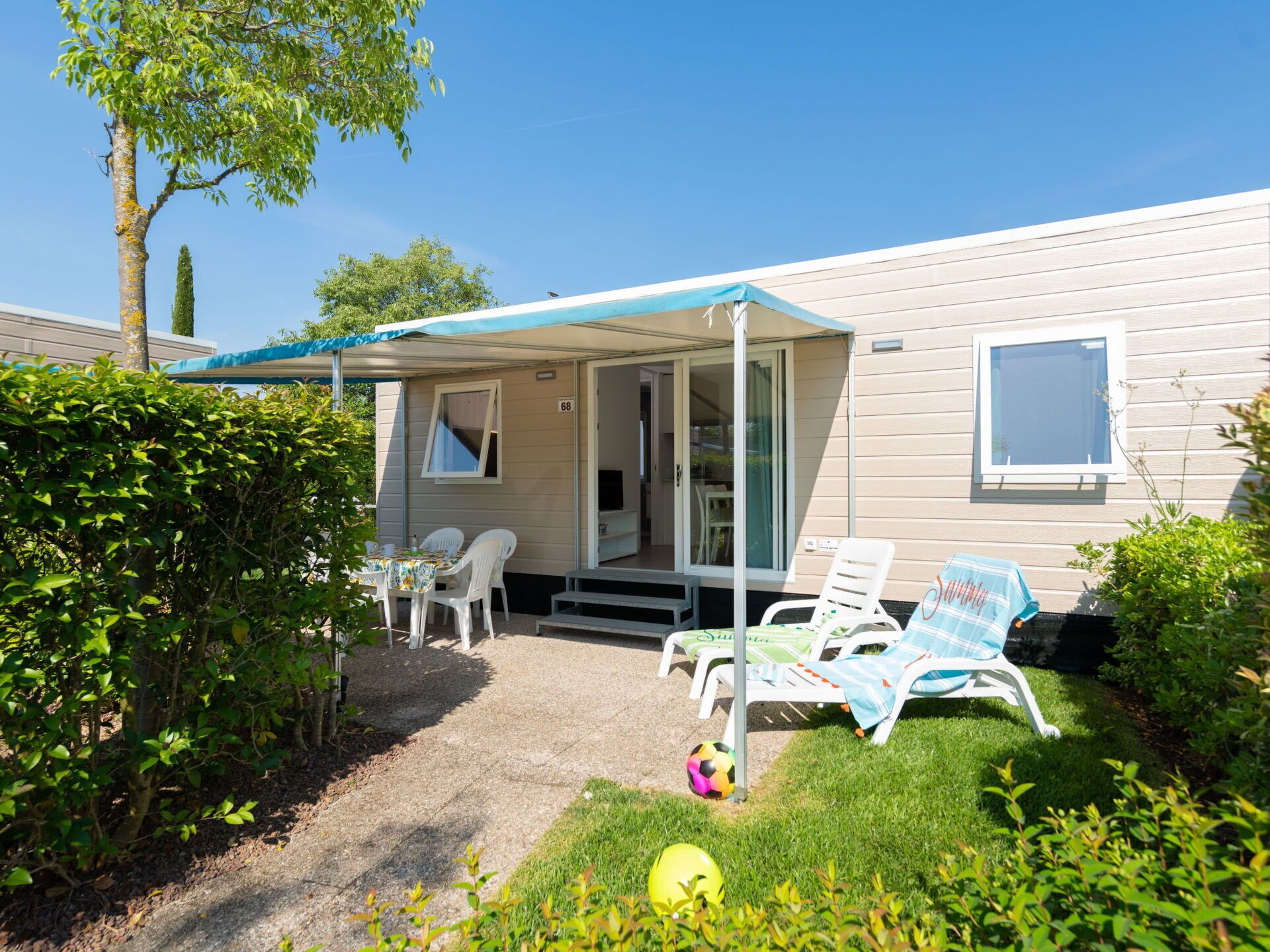 A mobile home with a covered patio, outdoor seating, and a small garden area.