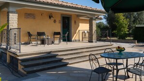 A building with a tiled roof, a green door, and a small outdoor seating area with a table and chairs. - Stunning private villa for 6 people with private pool, A/C, WIFI, TV, patio and pets allowed (Canale Monterano)