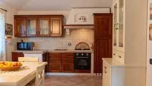 A kitchen with wooden cabinets, a microwave, an oven, and a tiled backsplash. - Stunning private villa for 6 people with private pool, A/C, WIFI, TV, patio and pets allowed (Canale Monterano)