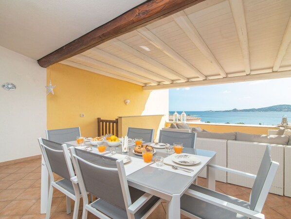 Un coin repas avec une table mise pour le petit-déjeuner, donnant sur une plage et la mer.
