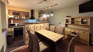 A compact kitchen with a stone backsplash, a built-in microwave, and a black range hood.