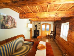 Cozy cabin-like atmosphere with a warm fireplace, comfortable sofa, and traditional decor.