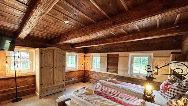 A wooden cabin bedroom with a bed, bedside lamps, and a wardrobe.