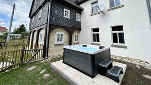 A two-story house with a hot tub in the backyard.