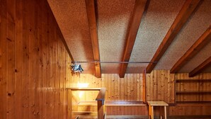 Ein Holzinnenraum mit schrägen Decken, Holzwänden und einer Bank.
