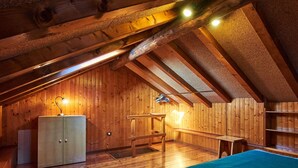 Ein gemütliches Schlafzimmer im Dachgeschoss mit Holzwänden, einem Bett, einem Schreibtisch und einem Schrank.